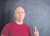 Man holding tin with the words "Money please" chalked on the board behind him